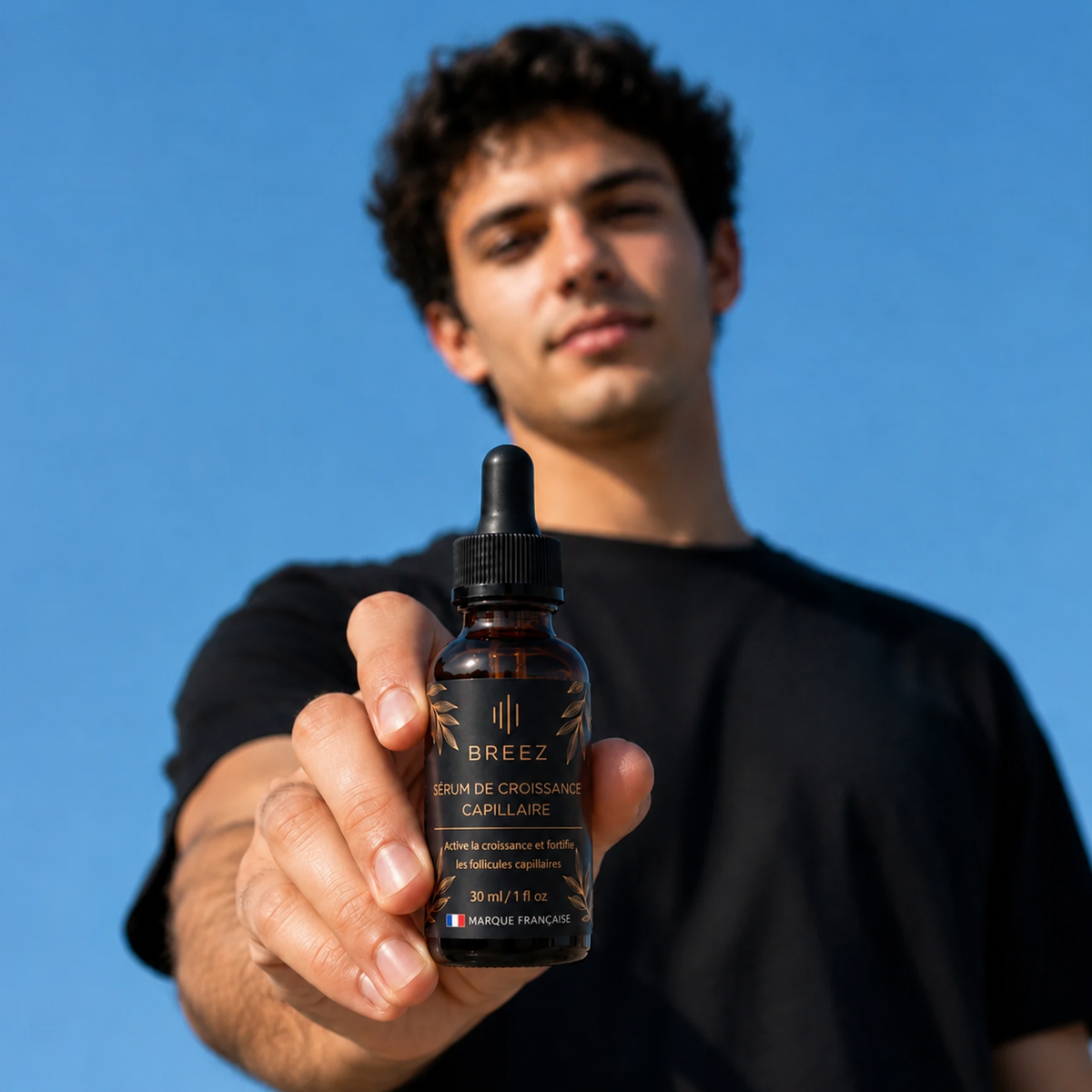 Homme présentant le flacon de sérum anti-chute BREEZ devant un ciel bleu