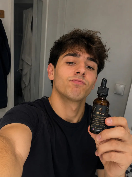 Jeune homme souriant tenant le flacon de serum BREEZ.