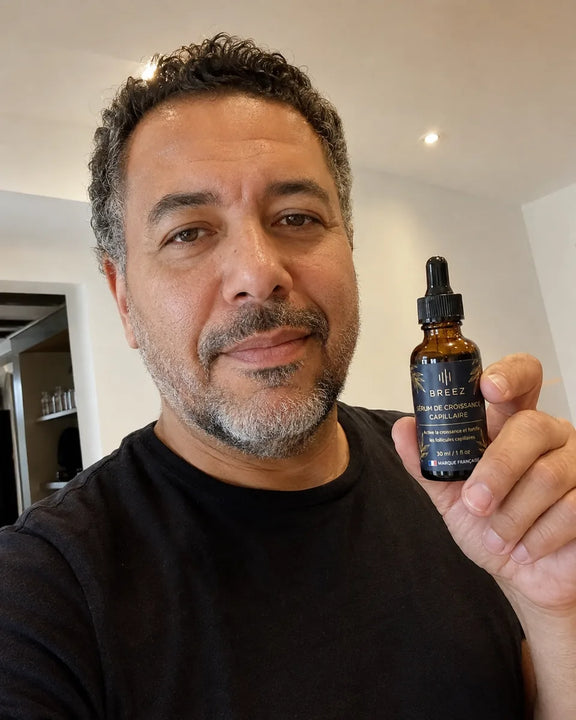 Client BREEZ aux cheveux boucles tenant le flacon de serum.